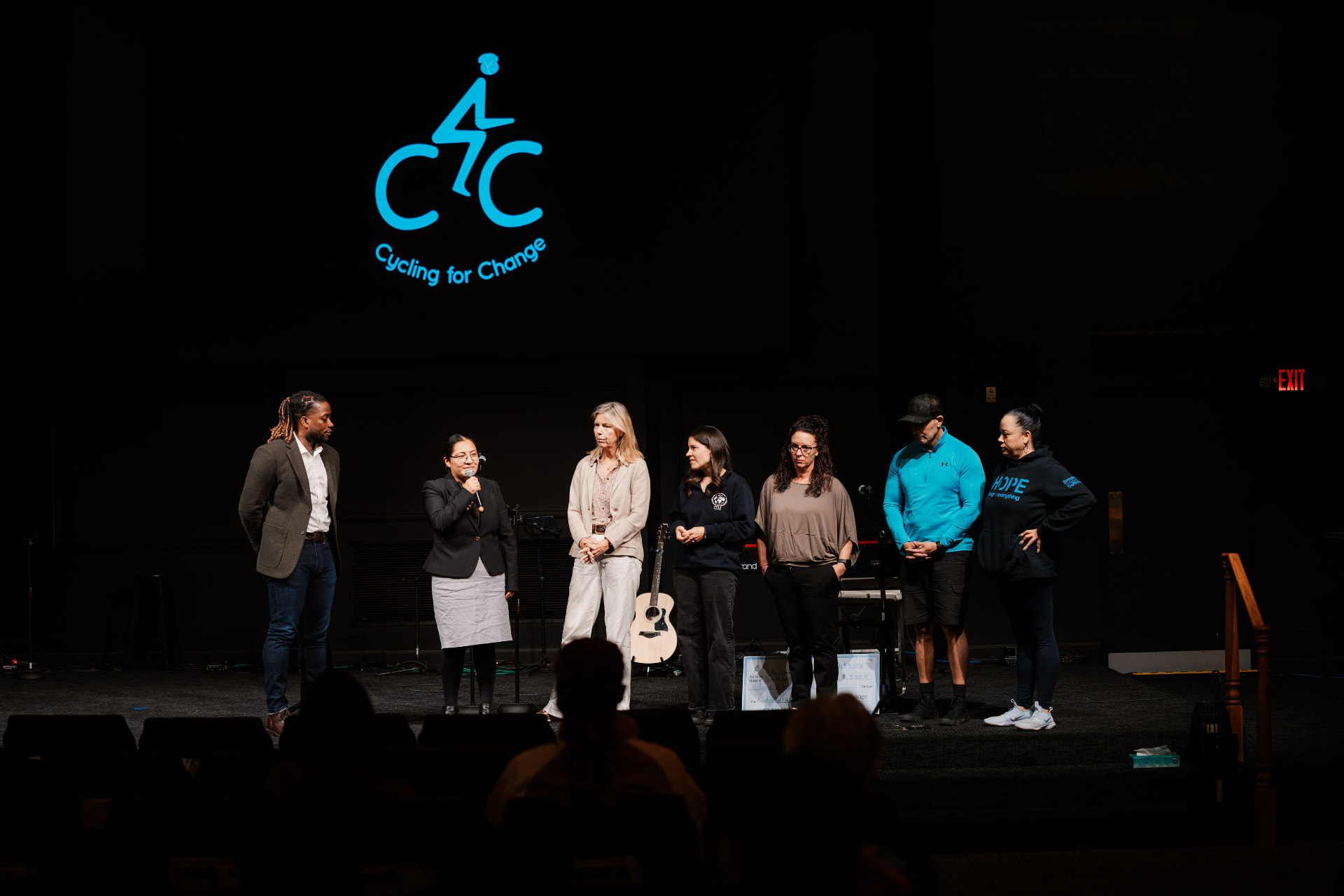 Speakers on stage beneath the Cycling for Change logo