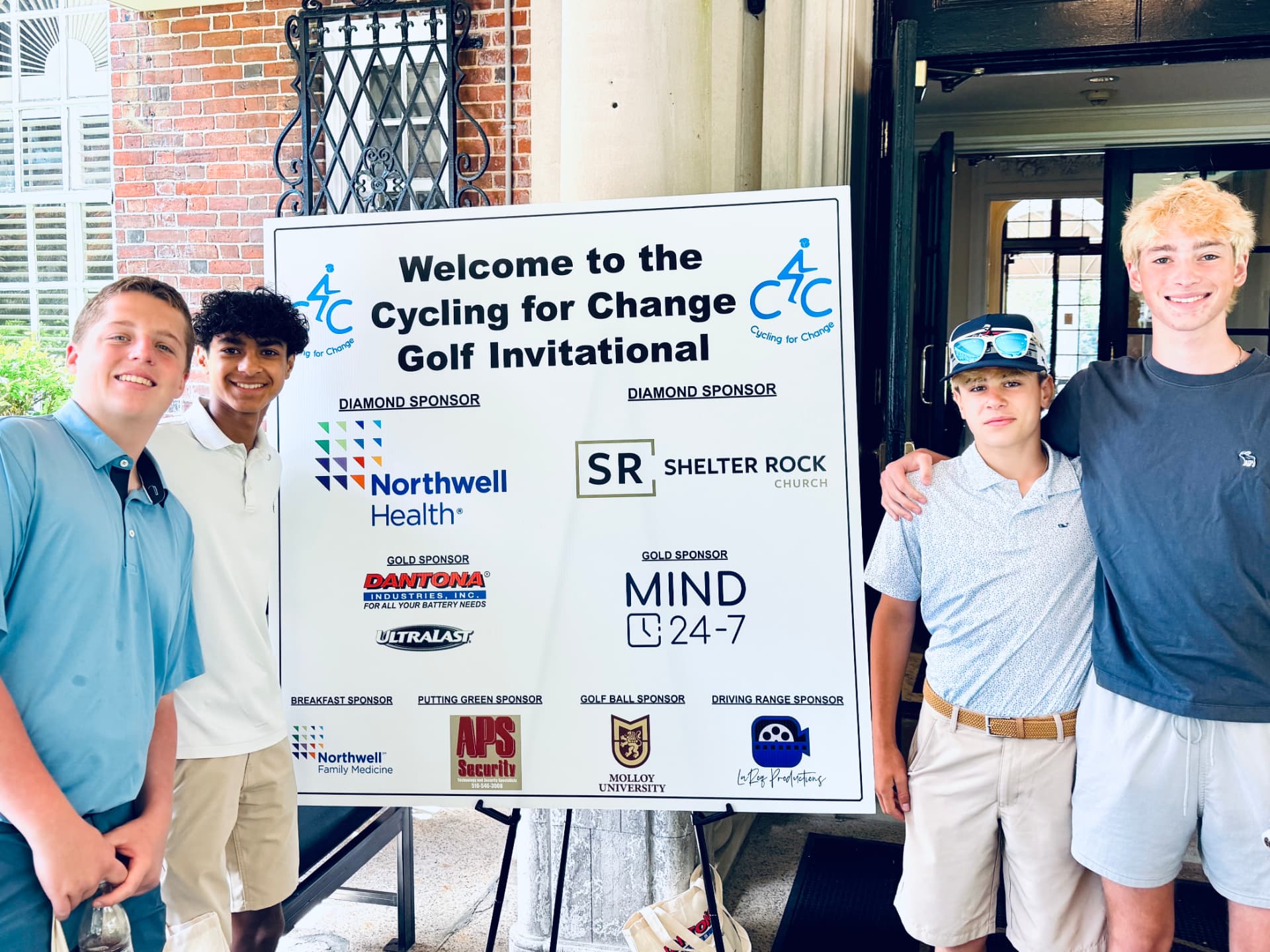Volunteers beside the Cycling for Change Golf Invitational welcome sign
