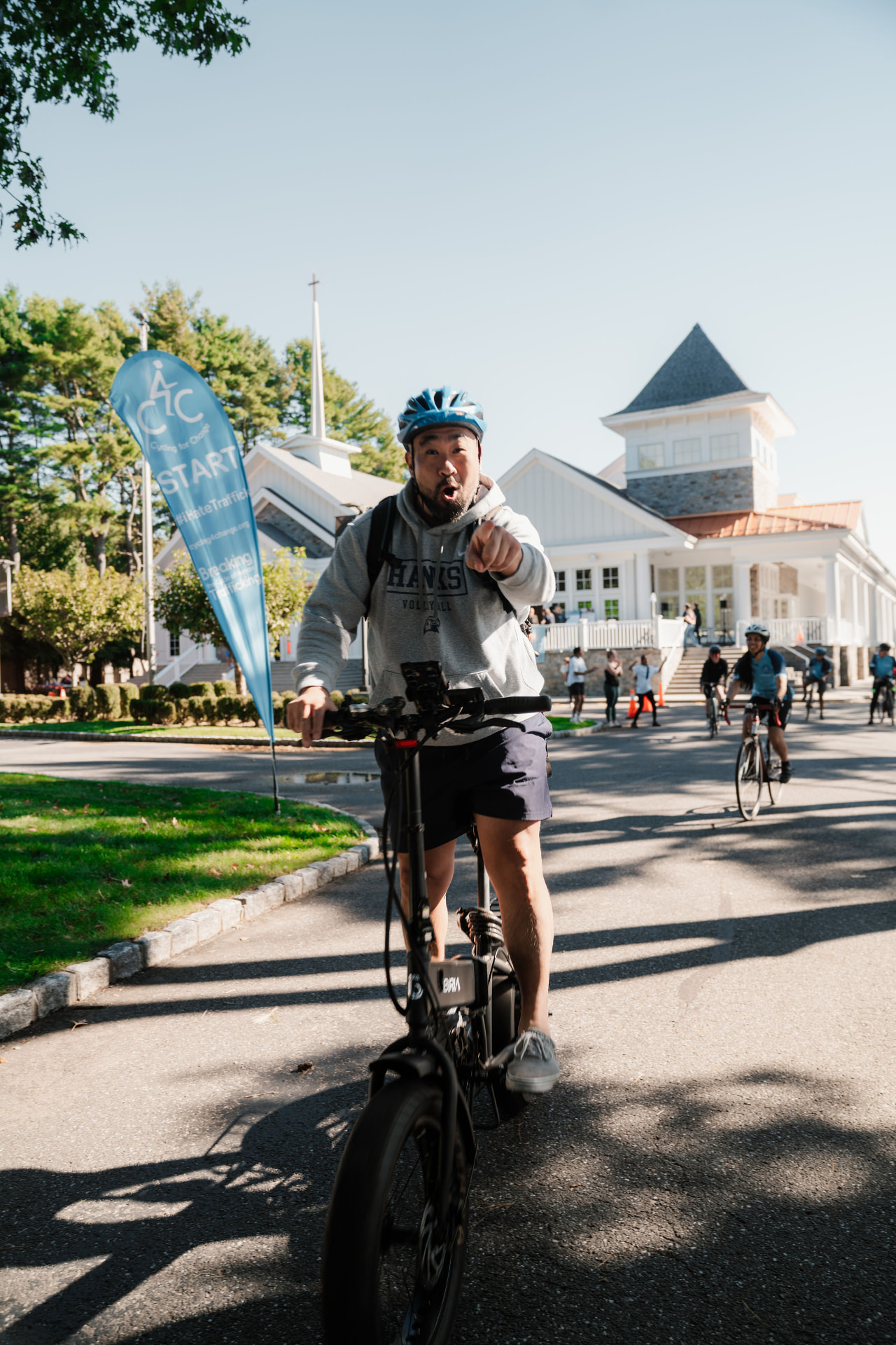 Rider on an e-bike pointing at the camera near the start flag