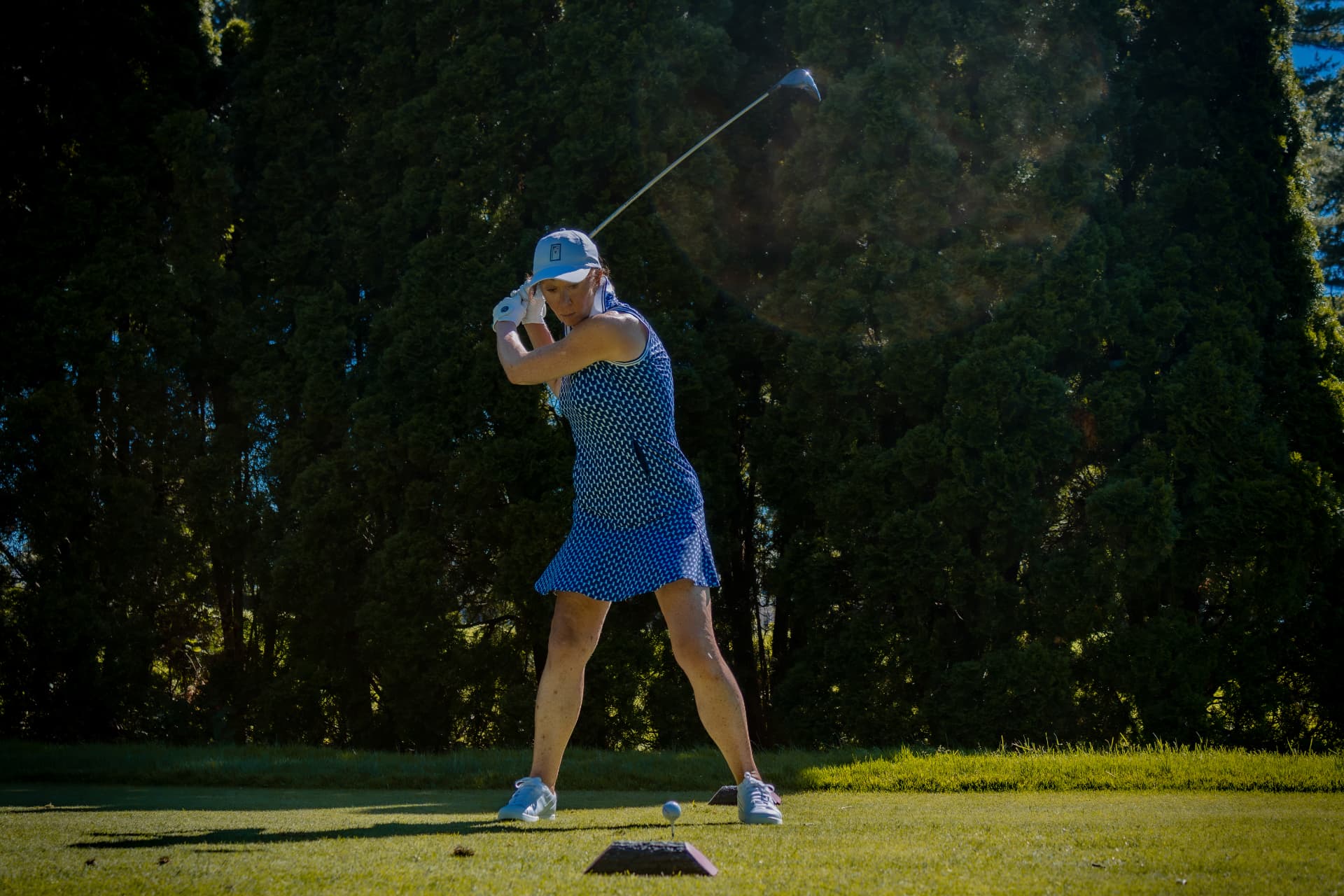 Golfer at the top of her backswing on the tee